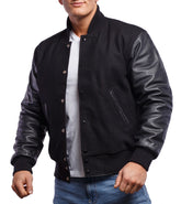 A man wearing a black varsity jacket with leather sleeves and a wool body, featuring a button-up front and side pockets.